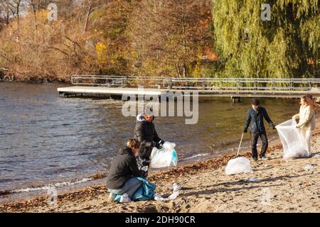 Männliche und weibliche Freunde sammeln Plastikmüll am See Stockfoto