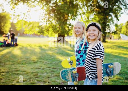 Portrait von lächelnden Freunden mit Skateboards im öffentlichen Park Stockfoto