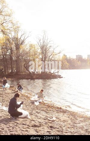 Männliche und weibliche Freunde sammeln Plastikmüll am See Stockfoto