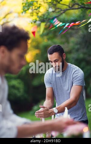 Männer decken brennende Kerzen während der Gartenparty Stockfoto