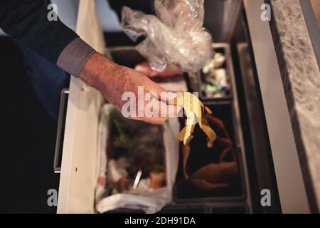 Beschnittene Hand eines älteren Mannes, der Müll in den Mülleimer warf Zu Hause Stockfoto