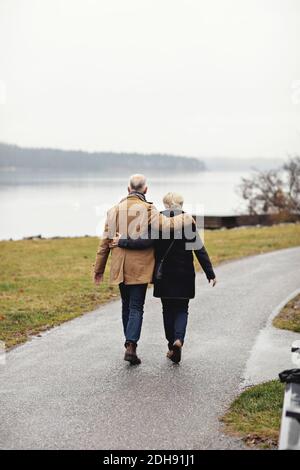 Rückansicht eines älteren Ehepaares mit Arm um den Gang Fussweg im Winter Stockfoto
