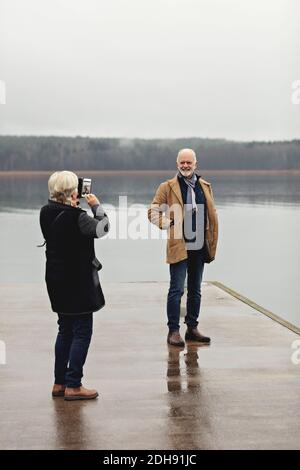 Die ganze Länge der älteren Frau fotografiert männlichen Partner am See Gegen klaren Himmel Stockfoto