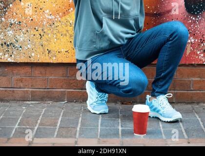 Frau, die an der Wand sitzt und Kaffee trinkt Stockfoto