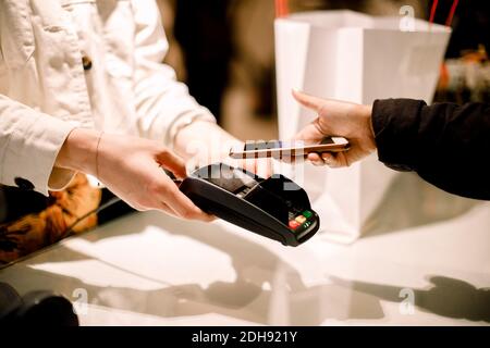 Kurze Hand von weiblichen Kunden, die über Smartphone bei zahlen Speichern Stockfoto