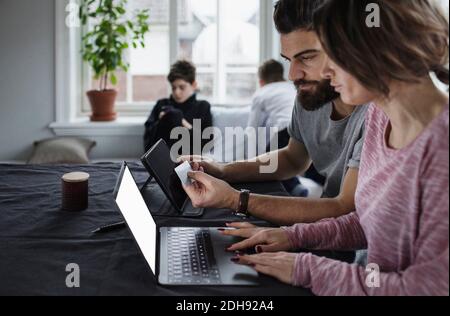 Mann und Frau einkaufen online mit Söhnen im Wohnzimmer Zu Hause Stockfoto