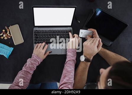 High-Angle-Ansicht des Mannes mit Kreditkarte, während Frau Tippen auf dem Laptop Stockfoto