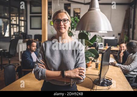 Porträt einer Geschäftsfrau mit gekreuzten Armen am Arbeitsplatz Stockfoto