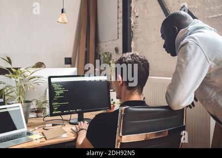 Computerprogrammierer durch Mitarbeiter, die am Arbeitsplatz an der Codierung arbeiten Stockfoto