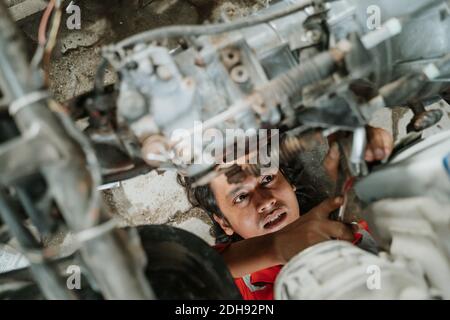 Portrait eines jungen asiatischen Mannes, der einen kaputten Automotor repariert Teil Stockfoto