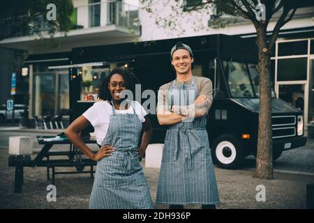 Portrait von lächelnden männlichen und weiblichen Besitzern, die gegen das Essen stehen LKW in der Stadt Stockfoto