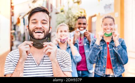 Glückliche Freunde lächeln mit geöffneten Gesichtsmasken nach dem Lockdown wieder öffnen - Neue normale Freundschaft Konzept mit Jungs und Mädchen mit Spaß zusammen Stockfoto