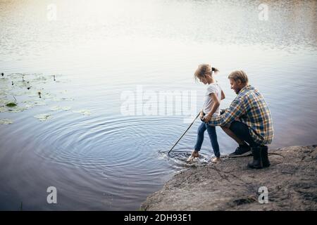 Vater hält Tochter beim Angeln am See Stockfoto