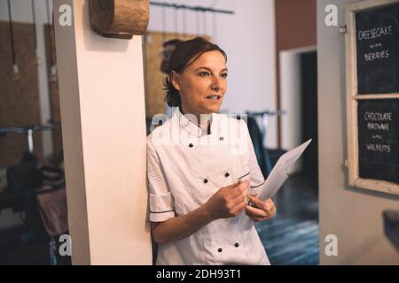 Reife Köchin schaut weg, während sie im Restaurant steht Stockfoto