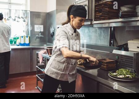 Männliche und weibliche Köche bereiten Essen in der kommerziellen Küche bei Restaurant Stockfoto
