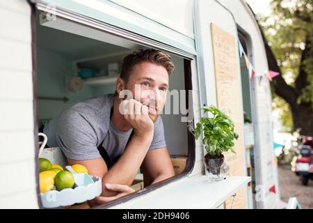 Nachdenklicher männlicher Besitzer, der durch das Fenster des Foodtrucks hinaus schaute Stockfoto