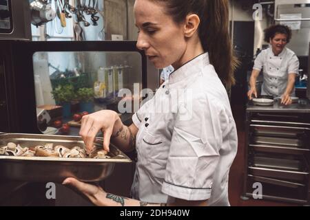 Seitenansicht des Küchenchefs, der Pilze im Ofen backen kann Küche Stockfoto