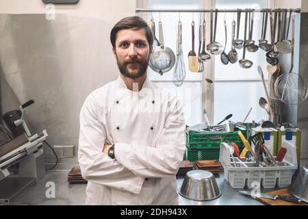 Portrait von selbstbewussten Koch mit Armen gekreuzt stehen in kommerziellen Küche Stockfoto