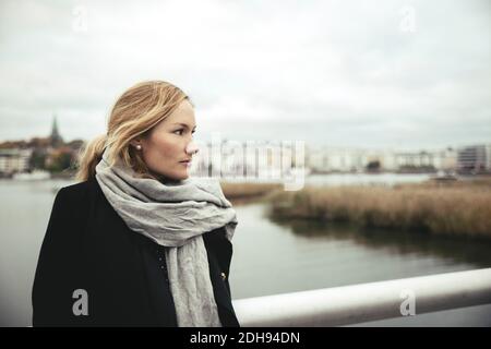 Eine durchdachte Geschäftsfrau mittleren Erwachsenen auf der Brücke über den Fluss Stockfoto