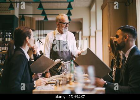 Der Kellner sprach mit Geschäftsleuten, während er am Tisch stand Restaurant Stockfoto