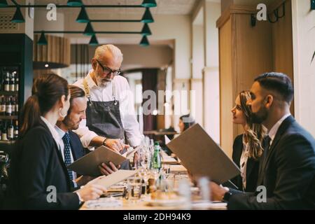 Der Kellner zeigt Geschäftsleuten im Restaurant die Speisekarte Stockfoto