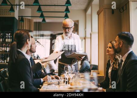 Der Kellner gab Geschäftsleuten im Restaurant ein Menü Stockfoto