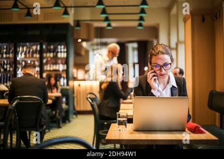 Geschäftsfrau in Brille telefoniert im Restaurant Stockfoto