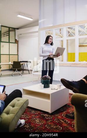 Junge Frau mit Laptop im kreativen Büro Stockfoto
