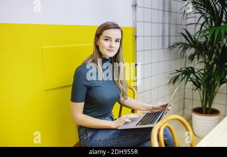 Porträt von selbstbewussten jungen Frau mit Laptop im Büro Stockfoto