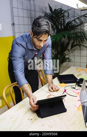 Junger Mann mit digitalem Tablet am Schreibtisch im kreativen Büro Stockfoto