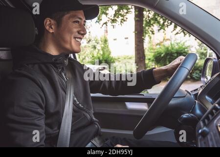 Lächelnder Lieferer fährt LKW Stockfoto