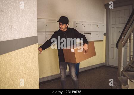Selbstbewusste Lieferung Mann mit Paket Klingeln Glocke für die Lieferung nach Hause Stockfoto