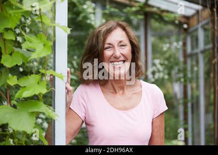 Porträt eines glücklichen älteren Gärtners, der am Eingang im Hof steht Stockfoto