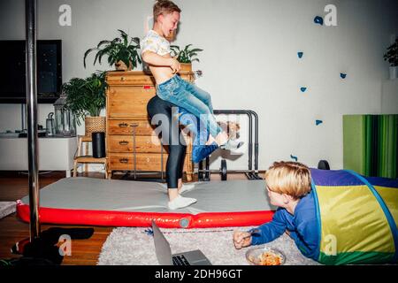 Männlich und weiblich üben Übungen, während Bruder Geschwister anschaut Im Wohnzimmer Stockfoto