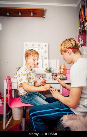 Junge Anwendung Nagellack auf Bruder im Zimmer Stockfoto