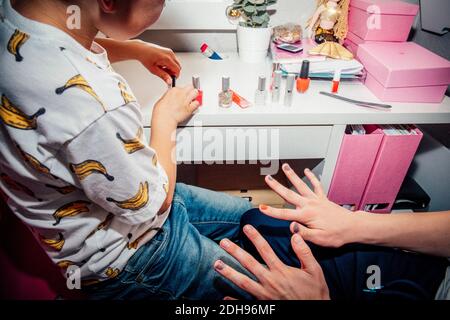 Junge Anwendung Nagellack auf Bruder im Schlafzimmer Stockfoto