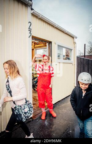 Mutter winkt Kindern vor dem Haus zu Stockfoto