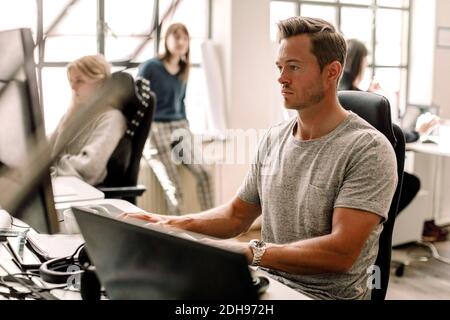 Männlicher Unternehmer, der am Arbeitsplatz am Computer arbeitet Stockfoto