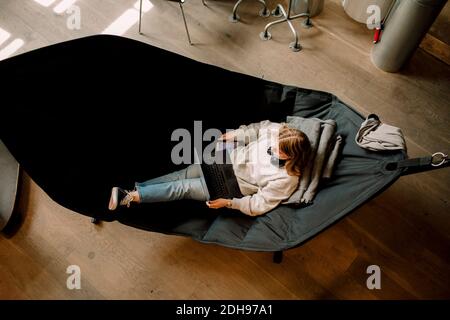 High-Winkel-Ansicht der Geschäftsfrau mit Laptop auf Hängematte sitzen Im Büro Stockfoto