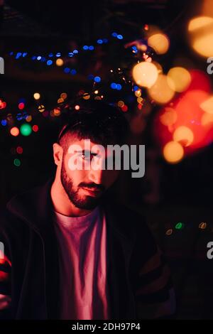 Porträt des selbstbewussten bärtigen Mann gegen beleuchtete bunte Lichter an Bar Stockfoto