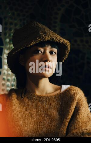 Porträt einer jungen Frau in brauner Kapuze im beleuchteten Restaurant Stockfoto