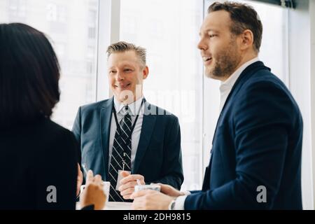 Lächelnde männliche Unternehmer diskutieren mit weiblichen Kollegen im Büro Seminar Stockfoto