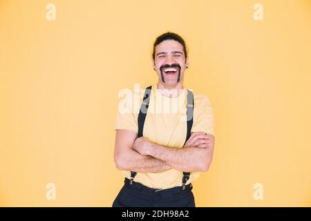 Glücklicher Mann, der vor gelbem Hintergrund steht Stockfoto