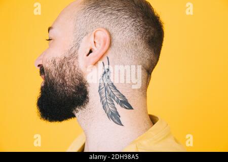 Nahaufnahme von Hals-Tattoo auf Mann vor farbigem Hintergrund Stockfoto