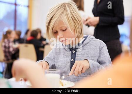 Junge, der in der Schulkantine zu Mittag gegessen hat Stockfoto