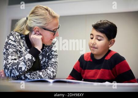 Mittlere Erwachsene Lehrer Unterricht Junge im Klassenzimmer Stockfoto