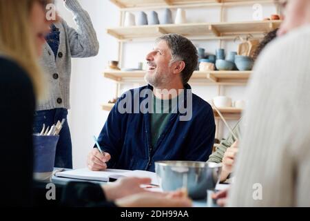 Lächelnd reifen männlichen Schüler im Gespräch mit weiblichen Lehrer in der Kunst studio Stockfoto