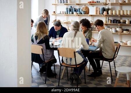 Weibliche Ausbilderin, die Zeichnung der Schüler am Tisch während der Kunst prüft Klasse Stockfoto