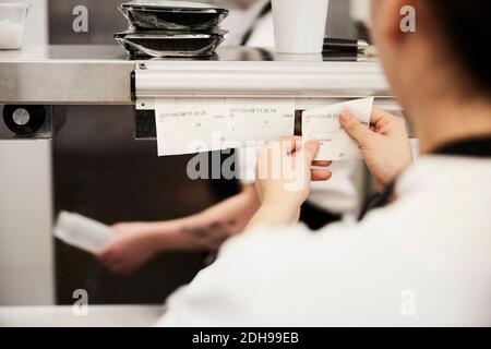 Zugeschnittenes Bild einer Köchin beim Lesen von Bestellscheinen im Werbespot Küche Stockfoto