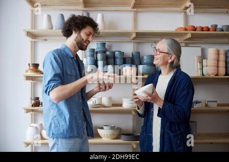 Mann und Frau diskutieren über Schüssel in Keramik-Klasse Stockfoto